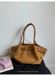 Detail of brown faux suede tote bag featuring decorative straps and vintage metal buckles