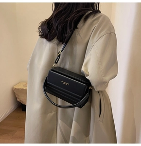 Model wearing a black geometric PU leather crossbody bag with a circular metal handle