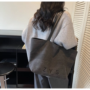 Detailed view of the dark grey striped canvas tote bag with ZYS embroidery on a model