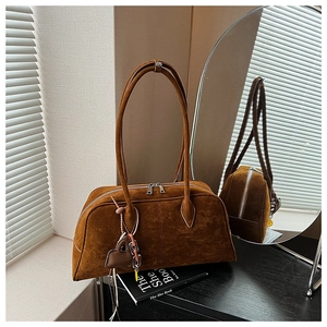 Detailstruktur der braunen Wildledertasche mit Doppelreißverschluss und Herzanhänger