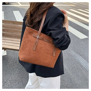 Dettaglio della borsa tote marrone in pelle opaca con fibbia metallica e logo