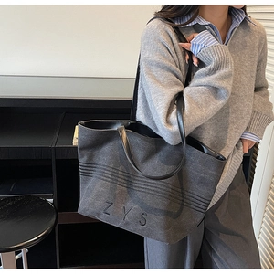 Detail of grey canvas tote bag with ZYS embroidery and black leather shoulder straps