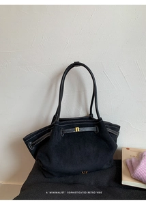 Detail of black suede tote bag featuring white contrast stitching and gold metal buckle