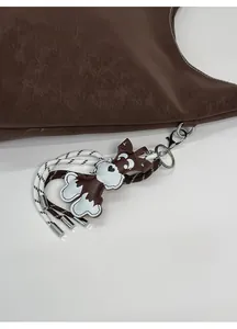 Detailed close-up of brown leather dog keychain with heart charm and woven rope on bag