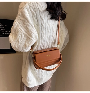 Brown leather box bag with magnetic closure shown in a lifestyle scene with white sweater