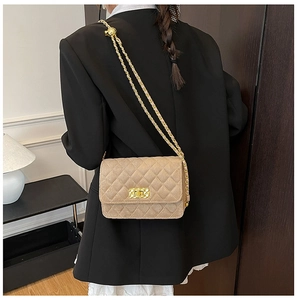 Detailed view of a beige quilted chain bag styled with a professional black blazer