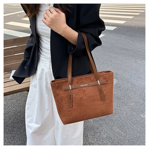 Dettaglio della borsa tote in pelle scamosciata caramello con manici in pelle e logo