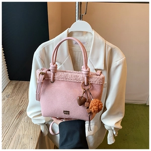 Dettaglio borsa a secchiello rosa scamosciata con bordo in peluche e ciondolo