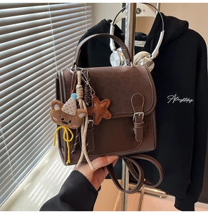 Close-up of brown vintage backpack with metal buckle and decorative charms details
