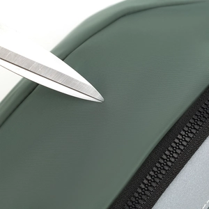 Close-up of scratch-resistant dark green nylon fabric with a sharp scissors test