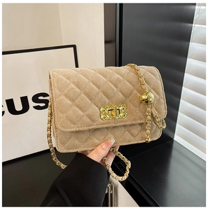 Detail of quilted beige flap bag featuring a gold clasp and metal chain strap decoration
