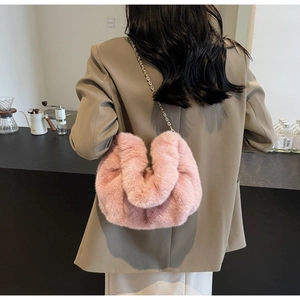 Pink faux fur cloud bag detail with elegant gold chain strap worn by a model