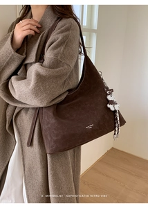 Detail view of dark brown suede tote bag with contrast stitching and dog charm