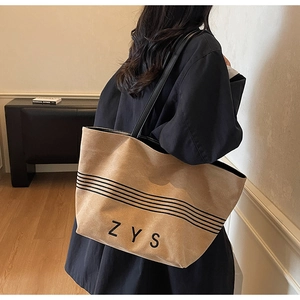 Detail shot of a large striped canvas tote bag with black leather straps and ZYS logo