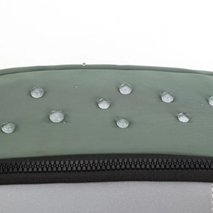Close-up of waterproof dark green fabric with water droplets and reflective safety strip