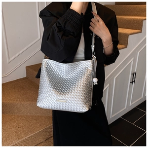 Detail der silbernen Web-Eimertasche mit Metalllogo und dekorativen weißen Perlen