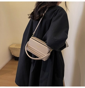 Detail of light beige leather crossbody bag with horizontal textures and top handle