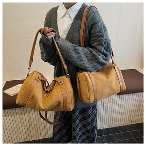Sac Boston en daim rétro marron et moutarde montré porté à l'épaule et à la main