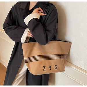 Detail of striped canvas tote bag with ZYS logo and thin black shoulder straps