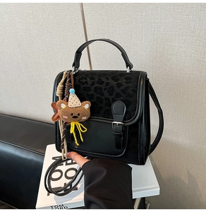 Detail view of leopard print texture on black leather bag with cute bear charm