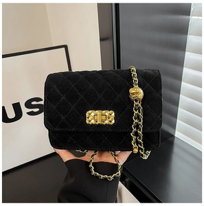 Detail of black quilted leather crossbody bag with gold chain and ball charm