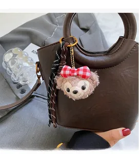 Détail du sac seau en cuir PU marron avec charme en peluche et pendentif à franges