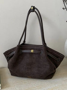 Retro brown suede tote bag with contrast stitching and gold logo on stone surface