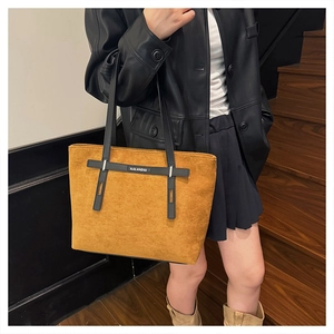 Dettaglio della borsa tote in pelle scamosciata marrone con tracolla in pelle nera