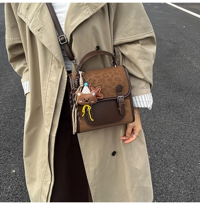 Detail of vintage brown leopard print backpack with plush lion charm on a khaki trench coat