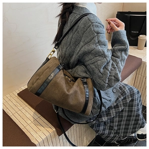 Détail d'un sac Boston vintage en daim marron avec garniture en cuir noir et boucles dorées