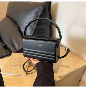 Detail showing the embossed texture and gold hardware on black leather box bag