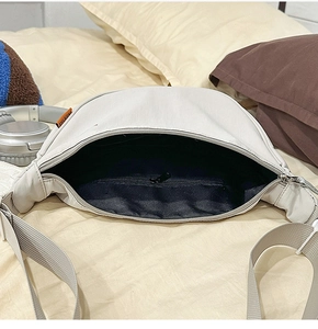 Dettaglio della borsa a mezzaluna in nylon bianco crema con fodera e etichetta arancione