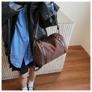 Détail d'un grand sac Boston en similicuir suédé marron porté par un mannequin