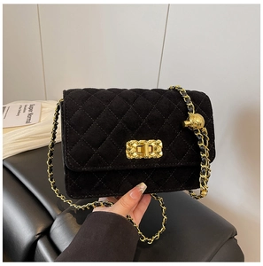 Close-up of black quilted shoulder bag with gold chain strap and metal turn-lock