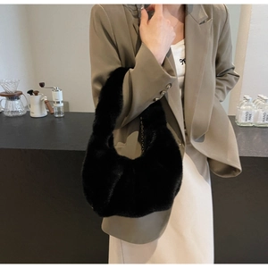 Close-up of a luxury black faux fur hobo bag with a stylish chain strap in a cafe setting