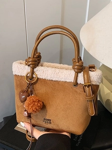 Secchiello in camoscio marrone con bordo in shearling e ciondoli su sfondo caldo