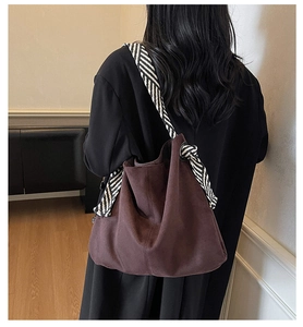 Deep brown suede tote bag featuring a striped wide strap and unique knot detail