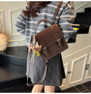 Detail of leopard print crossbody bag featuring twin buckles and a cute plush bear charm