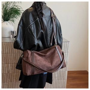 Détail du sac Boston rétro en daim marron avec bandoulière en cuir porté par un modèle