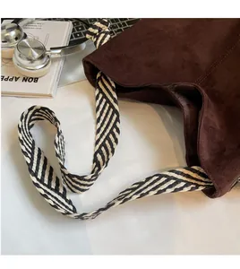 Macro shot of dark brown suede tote bag with black and white woven rope shoulder strap