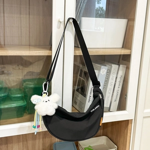 Dettaglio della borsa a mezzaluna nera con orsetto di peluche e ciondolo arcobaleno