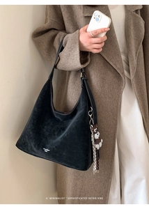 Detail of black large capacity hobo bag with cracked leather texture and cute puppy charm