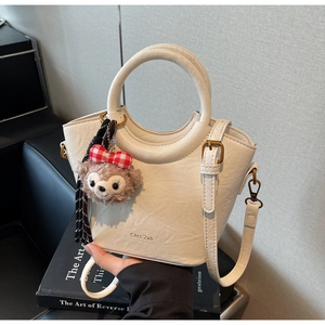 Détails d'un sac seau blanc avec poignée ronde et pendentif en peluche d'ours
