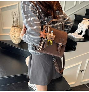 Rear view of a brown vintage backpack with bear charm on a model in a stairwell