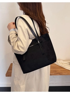 Borsa tote nera opaca minimalista con lunghi manici in pelle indossata da una modella