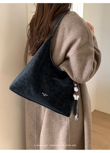 Detail of vintage black shoulder bag with white stitching and cute bear charm pendant
