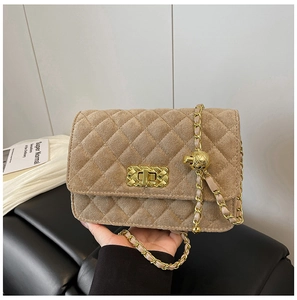 Detail of quilted suede crossbody bag with golden chain strap and adjustable ball ornament