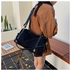 Détail du sac Boston en daim noir montrant la texture douce et les finitions dorées chic