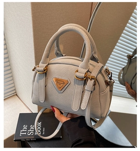 Close-up of light gray pebble leather handbag with triangle logo and gold hardware