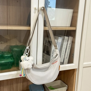 Borsa a tracolla a mezzaluna in nylon bianco con scritte rosse e ciondolo a orsetto